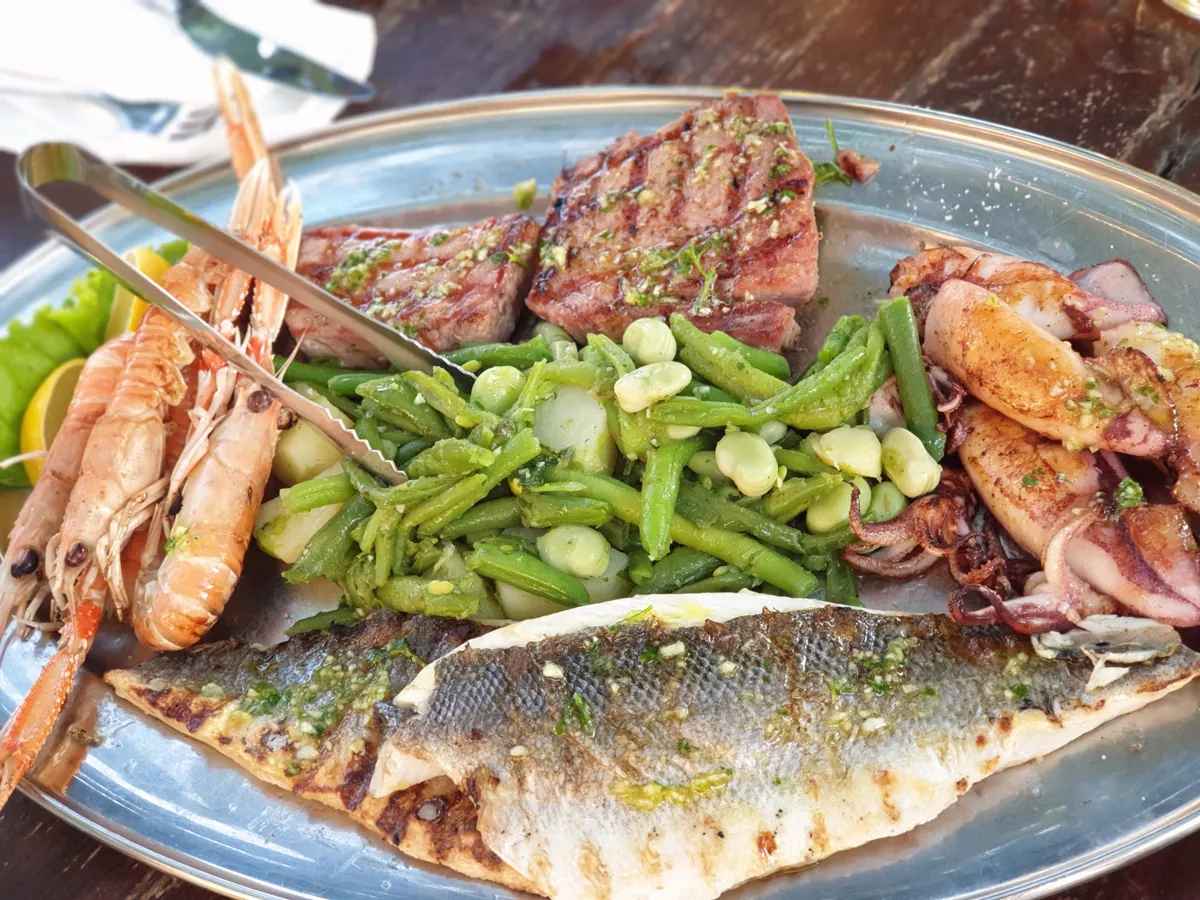 A whole grilled fish served with grilled courgette and spring onions on a plate
