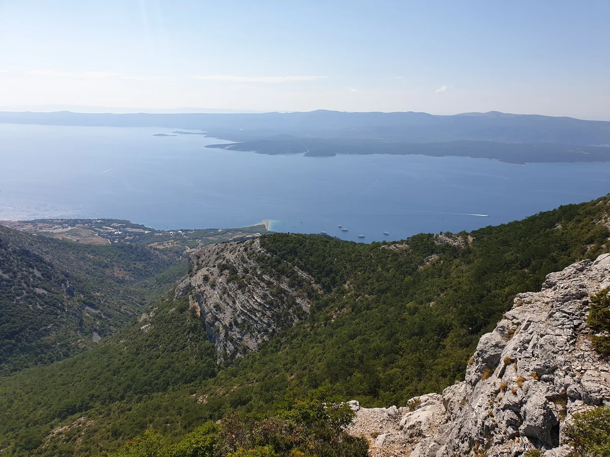 View from Vidova Gora on Brač looking down over the wooded ridge to Zlatni Rat beach and the sea, with Hvar island across the channel